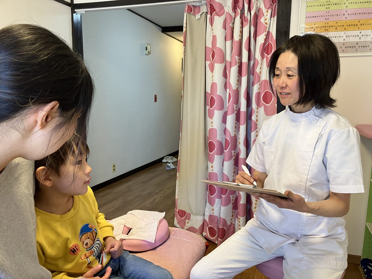 お子さま連れの方とお話する小川院長
