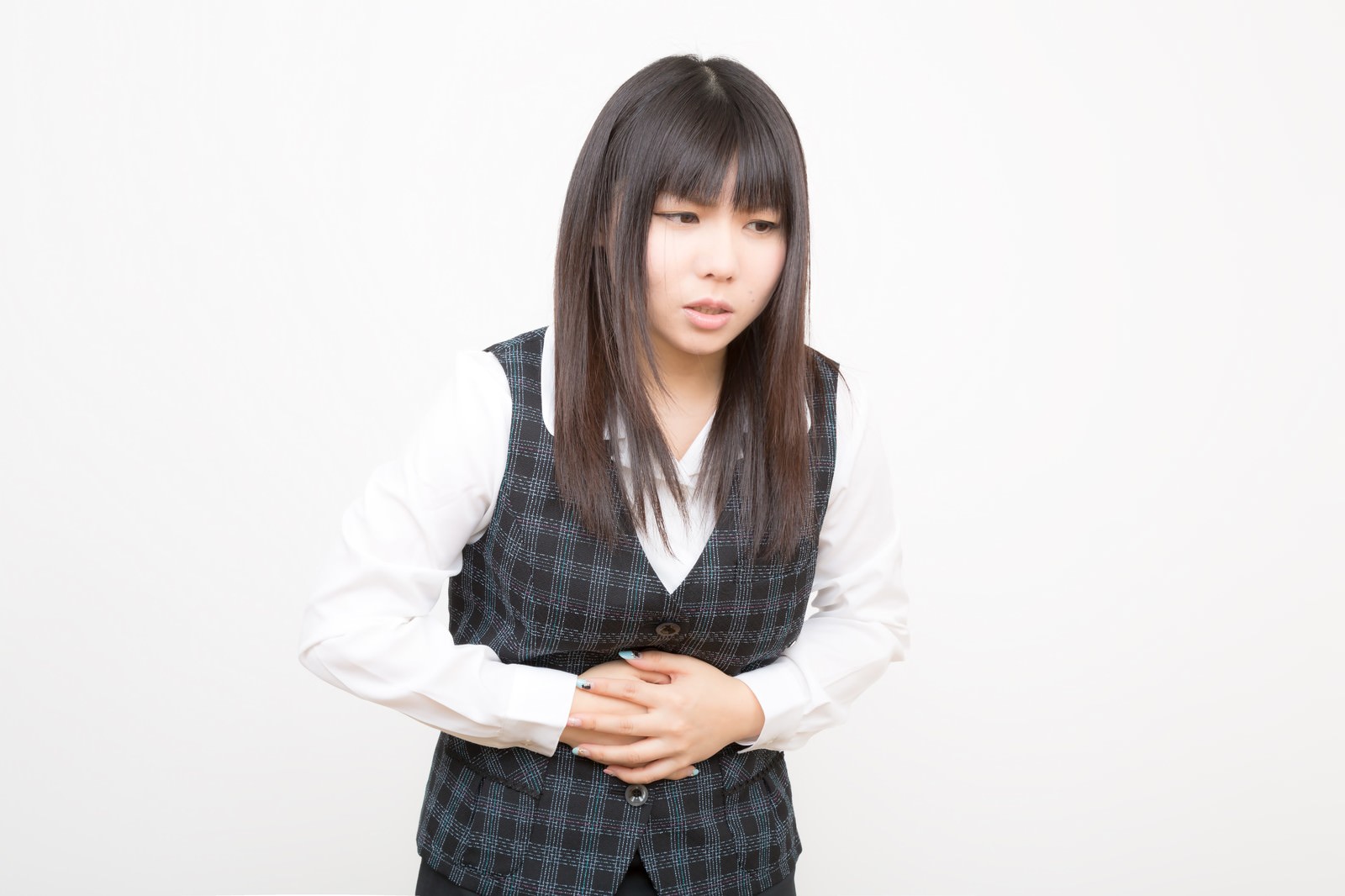 通勤中に胃腸の不調を感じておなかを押さえる女性